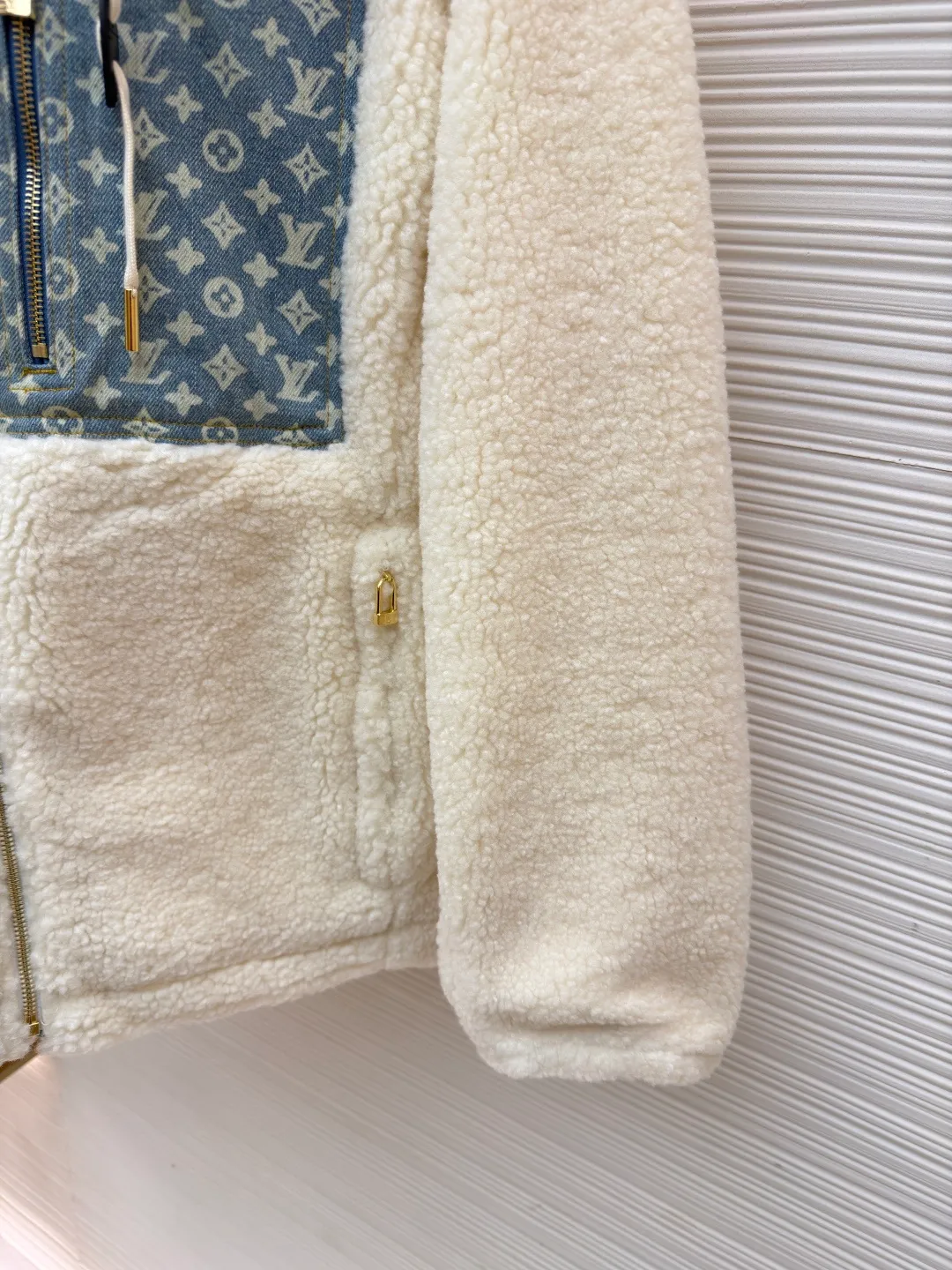 LOUIS VUITTON Letter jacquard splicing lamb wool ski hooded jacket ●Original version: purchased and developed by 26909 ●Item number: 1682241-C35 ●Fabric: lamb wool fabric ●Technology: jacquard production ●Color: off-white ●Version: fitted version ●Weight: about 1245 grams ●Size: 34-36-38-40-42-44 ●Description: The main body of this lamb wool spliced denim jacket is made of imported imitation lamb wool fabric, which has been processed by carding and shaping processes. The wool feels fluffy and soft and is not easy to shed and pill. The fabric has a uniform weight and has both warmth retention and breathability. The neckline, placket and chest pockets are spliced ​​with classic presbyopic denim. The denim is enzymatically washed to create a natural aged texture. The presbyopic pattern is embossed, making the texture three-dimensional and not easy to fall off. The body adopts a loose hooded fit, with a built-in shaping lining on the brim and an adjustable drawstring design; a custom metal zipper is used at the placket, and the chain teeth are gold-plated for smooth pulling and anti-oxidation. The edges of the pockets are reinforced with double stitching, and the splicing of lambswool and denim is made by hand caulking. The stitching is fine and smooth. Every detail is strictly controlled, showing the craftsmanship and quality of high-end clothing. The overall wiring is straight and delicate, the fabric is comfortable and soft, and the color is consistent without color difference. It can be matched with the same style to create a fashionable look and control various occasions. Customized accessories, complete with three standards, same style for men and women!